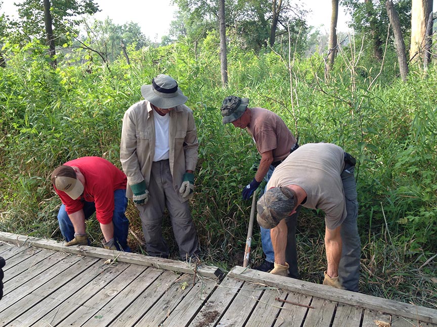 A group of men who appear to be fixing a wooden bridge