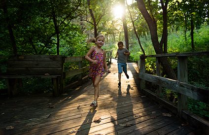 A couple of kids running across a wooden bridge