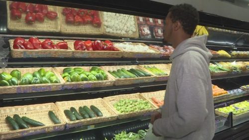 A man inspecting the vegetable section of the grocery store 