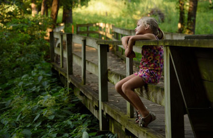 A picture of a little girl sitting on a bridge