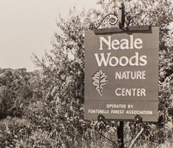 A picture of the forest with a sign that says "Neale woods nature center"