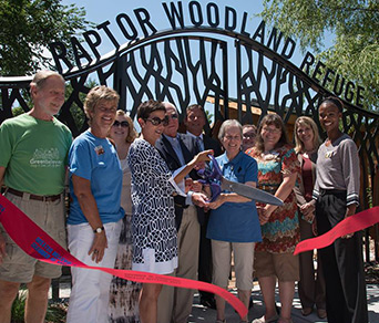 A group of people cutting the openign ribbon for Raptor woodland refuge