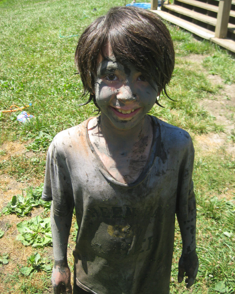 A young boy who appears to have been playing in the mud