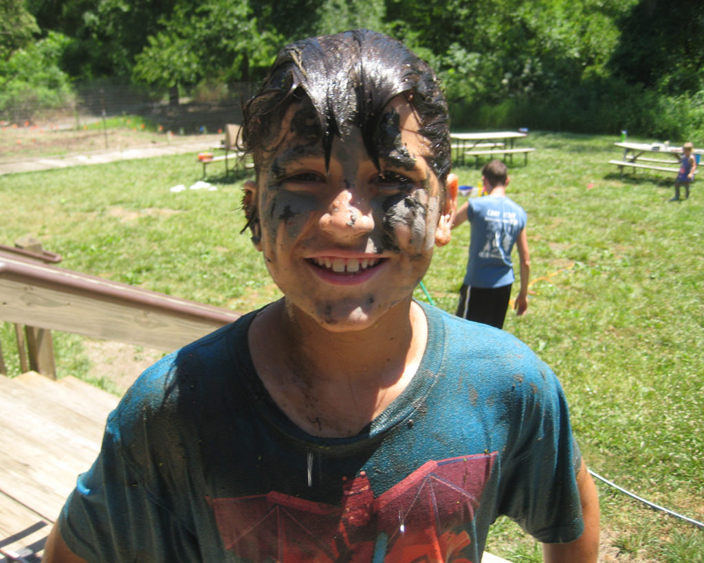 Picture of a young boy who appears to have mud on his face