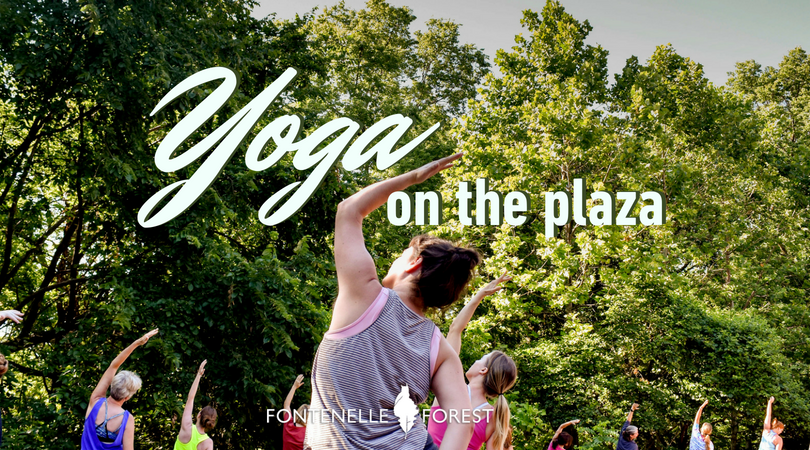 Picture of a group of people participating in yoga exersices with the text overlay " Yoga on the plaza"