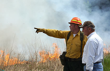 A picture of two men standing in front of a controlled burn