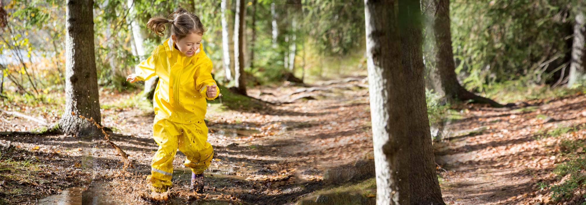 Picture of a little girl with a yellow rain jacket walking through the woods