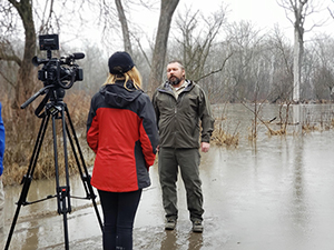 a picture of two people standing in flood water with a camera on a tripod behind them.