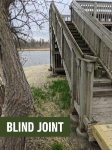 a picture of wooden stairs next to a tree. It has the text "BLIND JOINT" in a green label with white text.